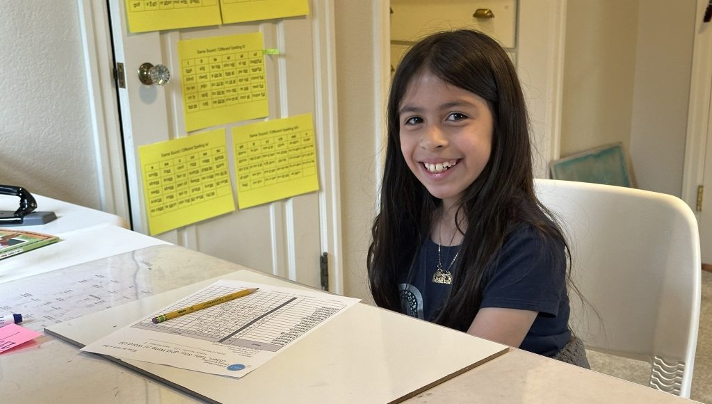 A smiling student at a tutoring table with learning materials