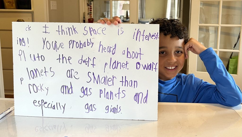 A student holding a whiteboard with a handwritten story